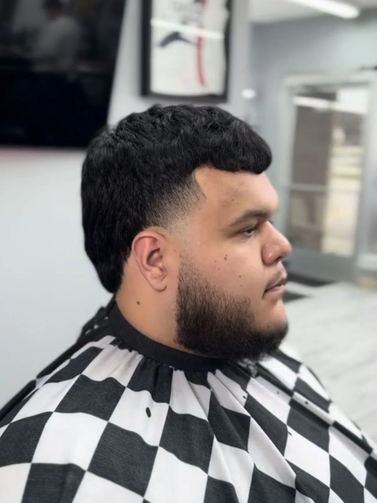 Black curly crop with a taper fade, sharp lineup and beard