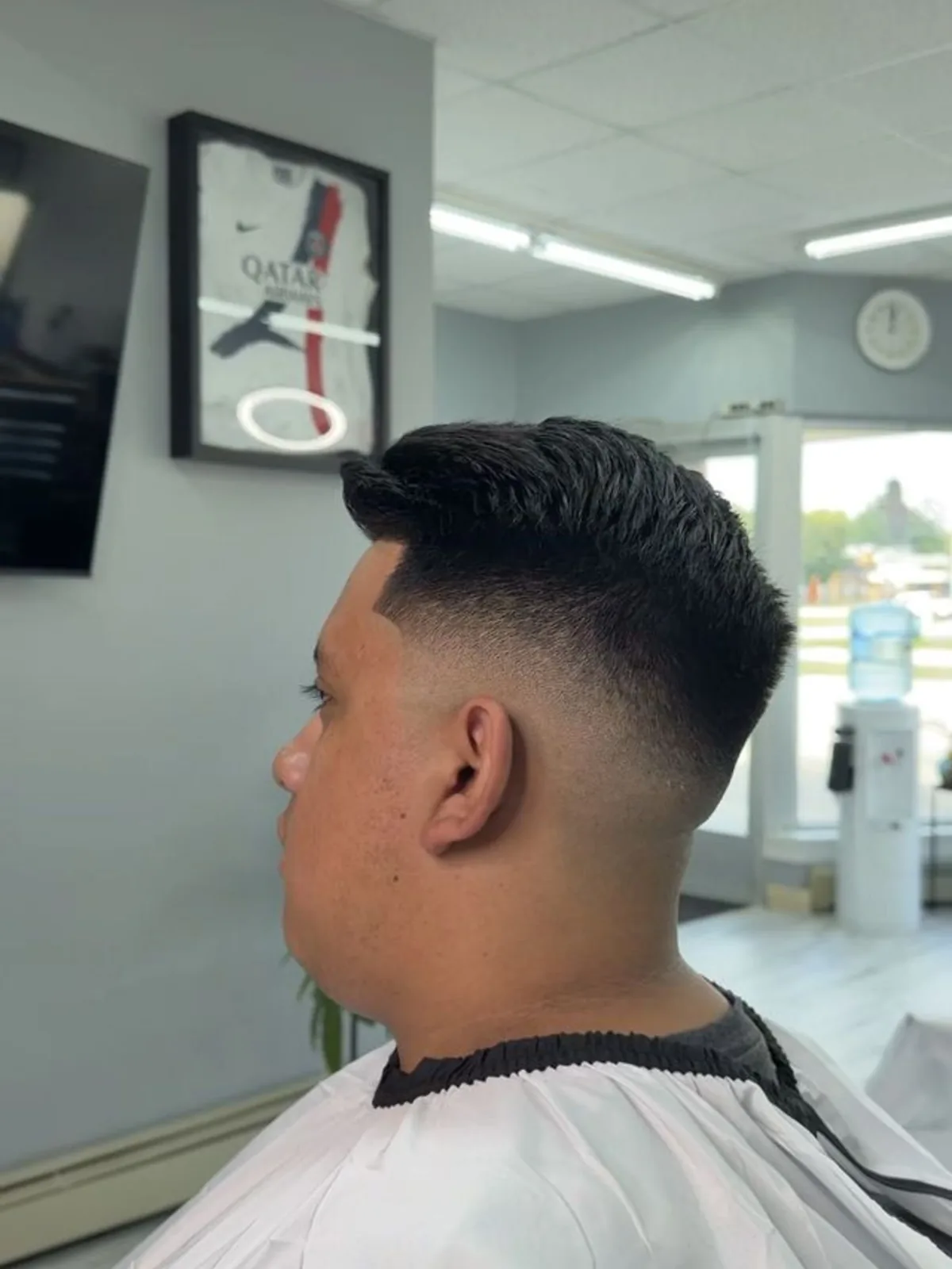 Black brushed-up quiff with a mid skin fade