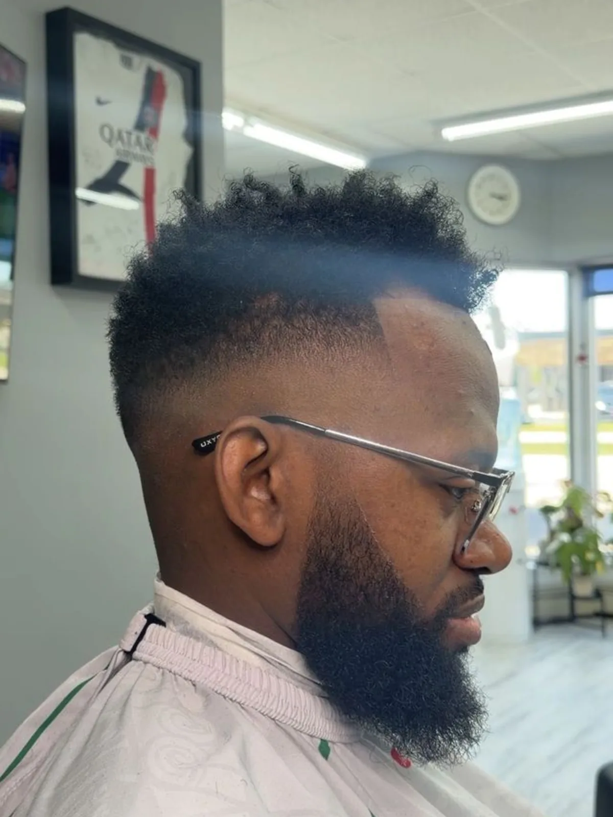 Curly top with a low fade and full beard