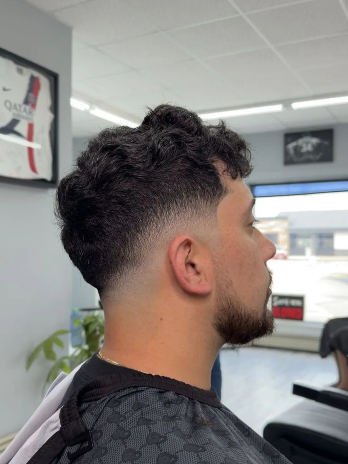 Curly top with a taper fade and trimmed beard