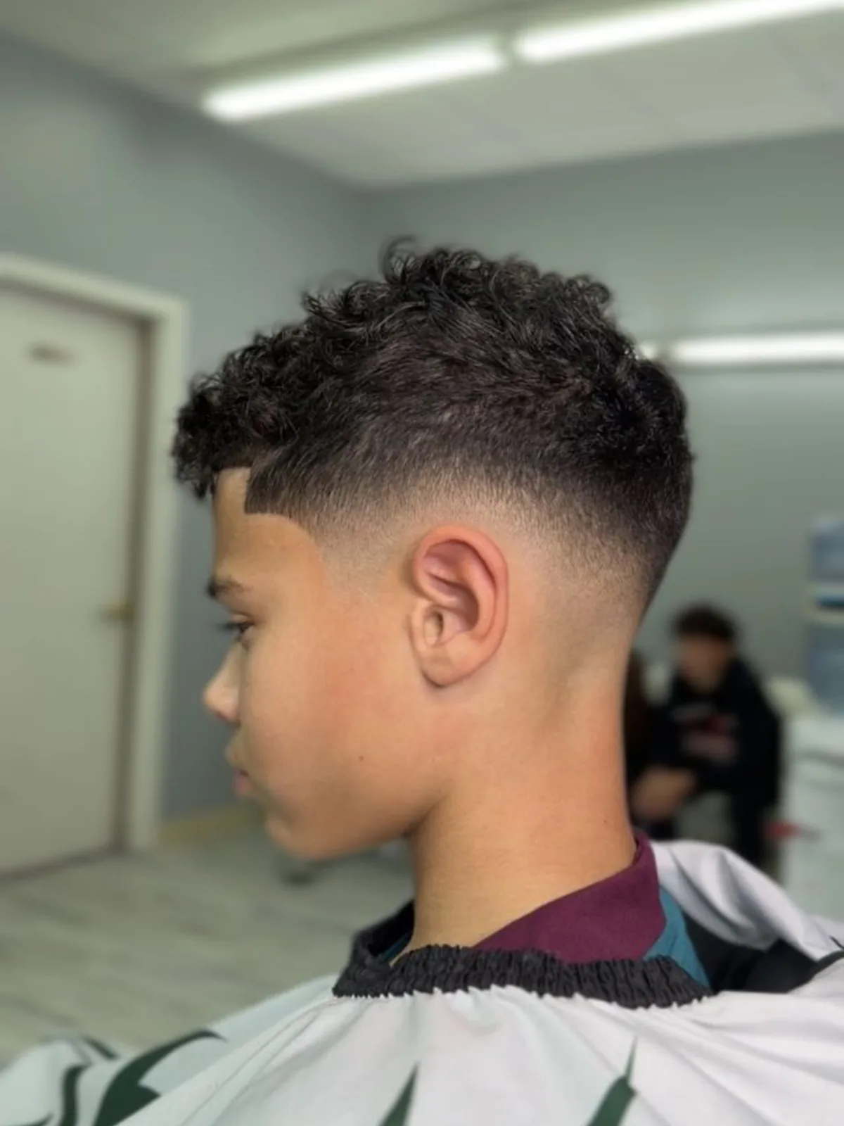Kids curly fringe haircut with a mid fade and lineup