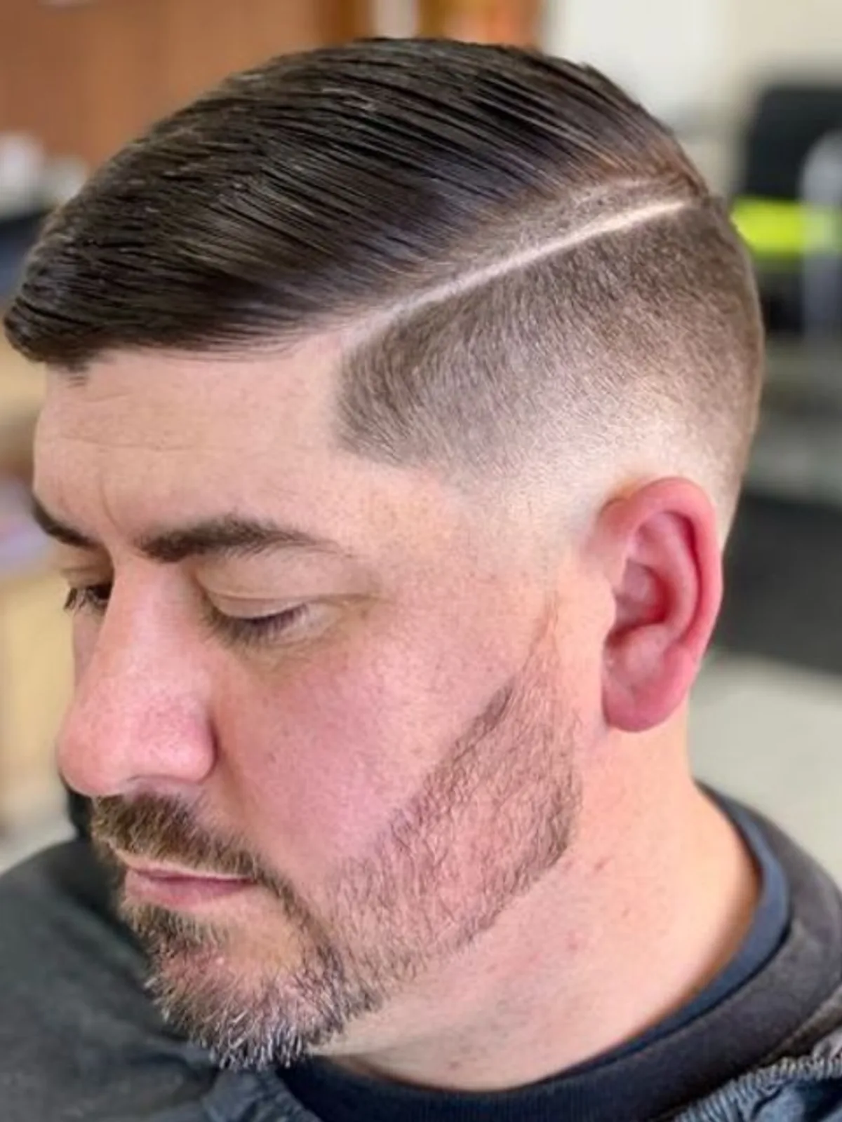 Comb over with a hard part, skin fade and beard