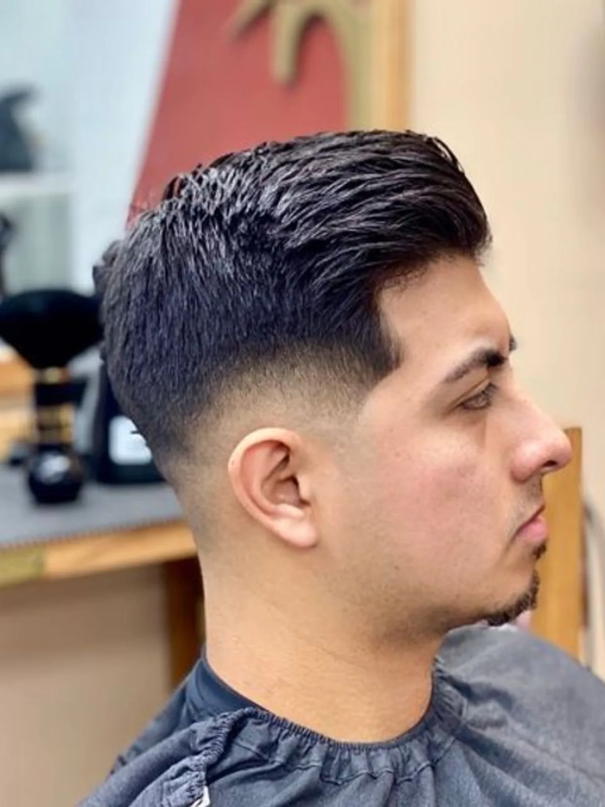 Slicked-back pompadour with a low fade and beard